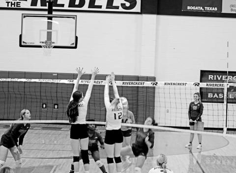 Rivercrest’s Emma Johnson and Anna Duvall jump for a block during Friday’s match against Detroit. The Lady Rebels will finish second in district play and open the playoffs next week against Linden-Kildare. TRIBUNE PHOTO / QUINTEN BOYD