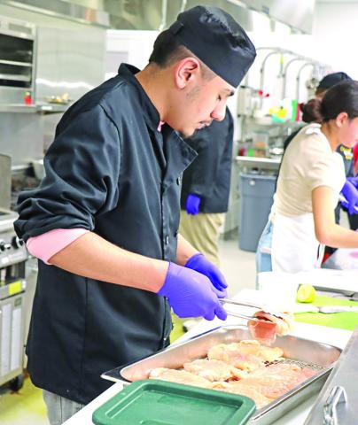 Senior Christian Terrones gets the chicken ready to be grilled