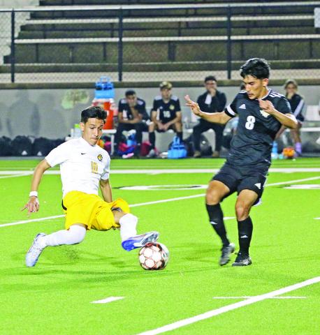 Mount Pleasant’s Ernesto Hernandez slides in to take possession away from Nacogdoches’ Bryan Morales during Thursday’s playoff game. Hernandez scored the game-tying goal near the end of the first half, but the Tigers fell to the Dragons in penalties, 3-2. TRIBUNE PHOTOS / QUINTEN BOYD
